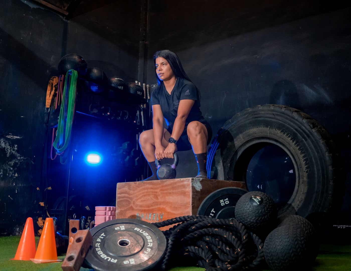 A woman mid-session, lifting a kettlebell in a training gym